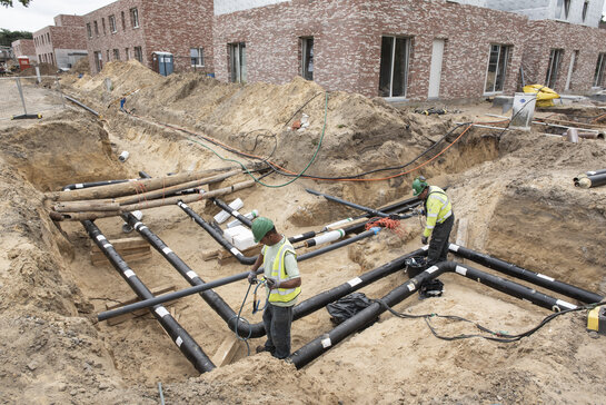 Techniekers aan het werk op de werf van een warmtenetproject