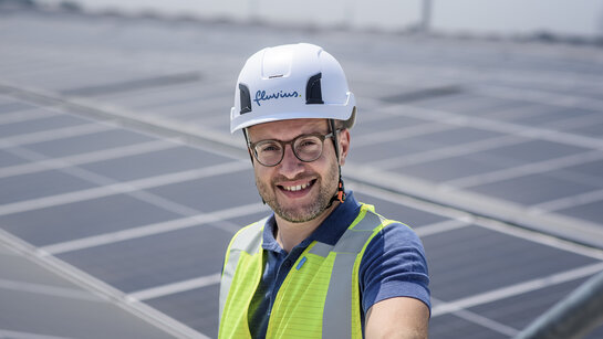 Fluvius medewerker met zonnepanelen op de achtergrond