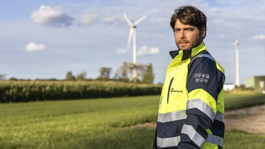 Fluvius medewerker met windmolen op de achtergrond