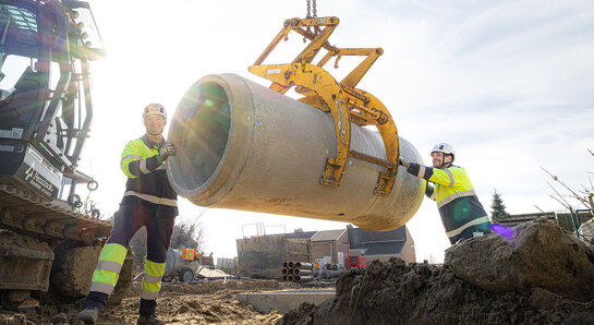 Sewage in the water cycle Sewer works where a crane is placing a concrete sewer pipe, with Fluvius technicians on site.