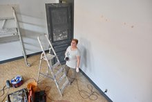 Vrijwilligers van Fluvius-Goede doelen steken handen uit de mouwen Vrijwilliger van Fluvius-Goede doelen staat klaar naast een ladder om de muren van een lokaal van De Voedselbanken te schuren.